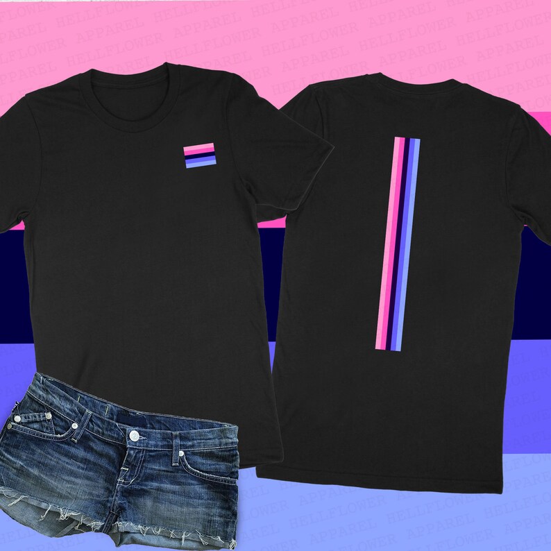 Pode incluir: Camiseta preta com uma pequena bandeira azul claro, rosa e branca no peito esquerdo e uma faixa vertical das mesmas cores nas costas. A camiseta est&aacute; sendo modelada com shorts jeans.