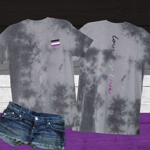 May include: Gray tie-dye t-shirt with a small black, white, and gray flag on the front and the words "love is love" written vertically on the back.