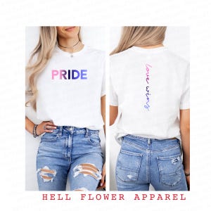 Pode incluir: Camiseta branca com a palavra "PRIDE" em cores do arco-&iacute;ris na frente e "love wins" em cores do arco-&iacute;ris nas costas.