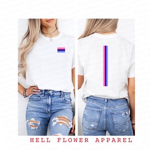 Pode incluir: Camiseta branca com um pequeno design de listras horizontais rosa, azul e preto na frente e um design de listras verticais nas costas. A camiseta est&aacute; sendo modelada por uma pessoa que est&aacute; usando jeans azul.