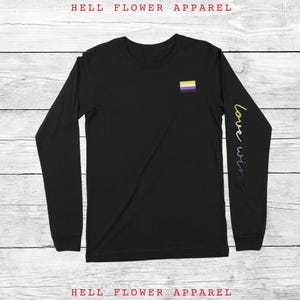 May include: Black long-sleeve shirt with a yellow, white, and purple flag on the chest and the text "love wins" on the sleeve.