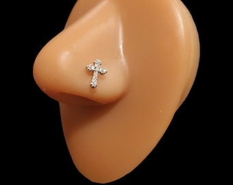 May include: A silver nose ring with a small, clear crystal cross design.