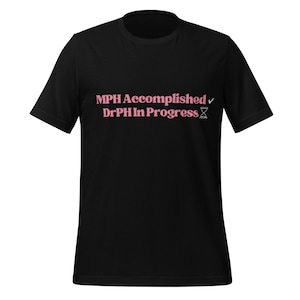 May include: Black t-shirt with the text "MPH Accomplished" and "DrPH In Progress" in pink lettering. The design includes a checkmark and an hourglass symbol. A casual, everyday wear tee.