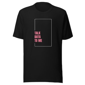 以下が含まれることがあります： 白い長方形のフレームの中にピンク色の「TALK DATA TO ME」という文字が入った黒いTシャツ。クルーネックと半袖のスタイルです。