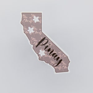 Puede incluir: Una pegatina de color marrón y rosa con estampado floral del estado de California con la palabra "Pinay" escrita en cursiva negra.