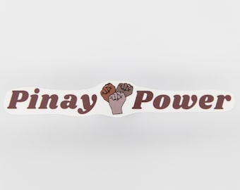 Könnte beinhalten: Weißer Aufkleber mit dem Text "Pinay Power" in braunen Buchstaben. Drei erhobene Fäuste in verschiedenen Hauttönen sind zwischen den Wörtern zentriert.