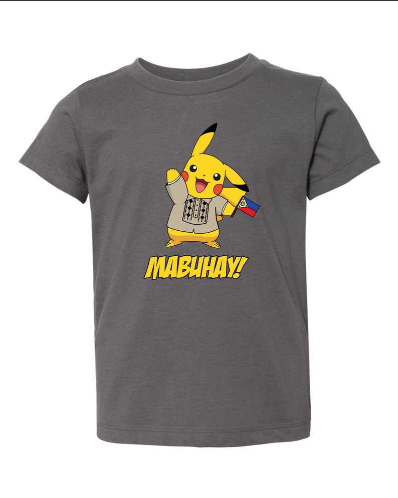 May include: A grey t-shirt featuring a yellow cartoon character wearing a traditional Filipino shirt and holding a Philippine flag. The text "MABUHAY!" is printed below the character.