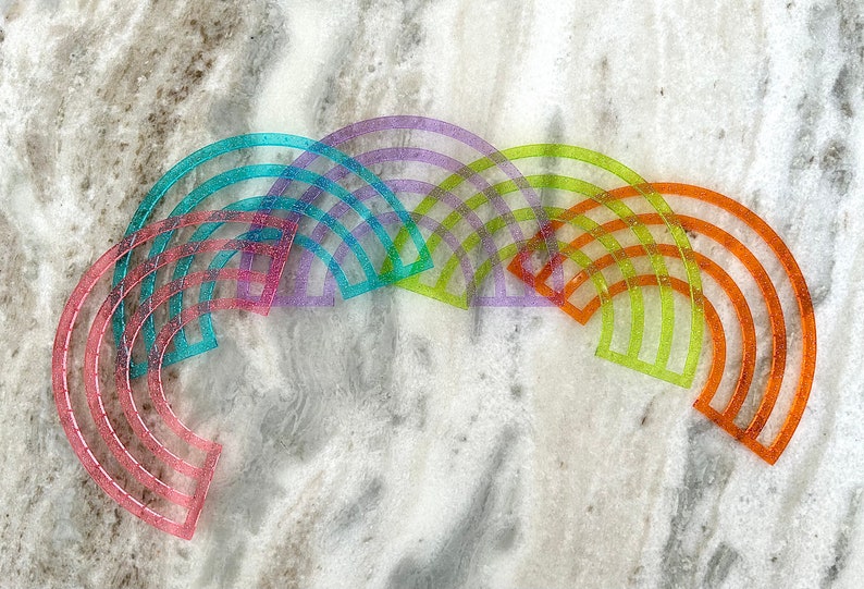 Pu&ograve; includere: Un set di sei archi in plastica arcobaleno, ognuno di un colore diverso, tra cui rosa, blu, viola, verde, giallo e arancione. Gli archi sono disposti a forma di semicerchio, con l'arco pi&ugrave; grande in basso e l'arco pi&ugrave; piccolo in alto.