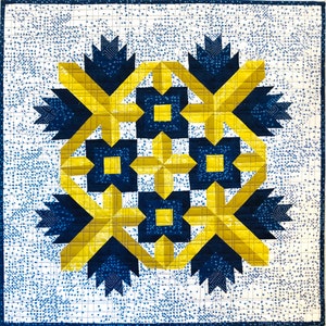 May include: A quilt block with a geometric design featuring yellow and blue squares and triangles. The block is set against a white background with a grid pattern.