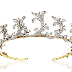 Op de afbeelding: Een delicate diamanten tiara met een bloemmotief, gezet in goud en zilver. De tiara heeft ingewikkelde krulwerk en een rij glinsterende diamanten.