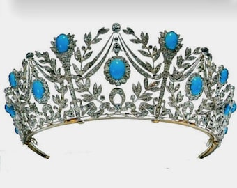 Könnte beinhalten: Eine silberne und goldene Tiara mit einem zarten floralen Design und türkisfarbenen Edelsteinen. Die Tiara ist auf einem weißen Hintergrund platziert.