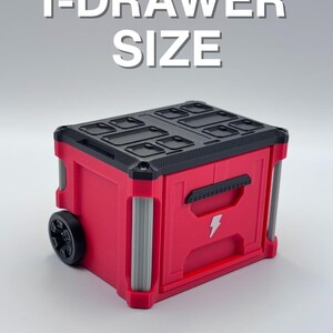 May include: A red and black storage container with a lightning bolt graphic and the text "1-DRAWER SIZE". The container has a black top with compartments, a handle, and a wheel on one side. The container has silver accents.