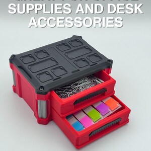 May include: Red and black two-drawer desk organiser with the text "GREAT FOR OFFICE SUPPLIES AND DESK ACCESSORIES." The top drawer contains paper clips, and the bottom drawer contains colourful sticky notes.