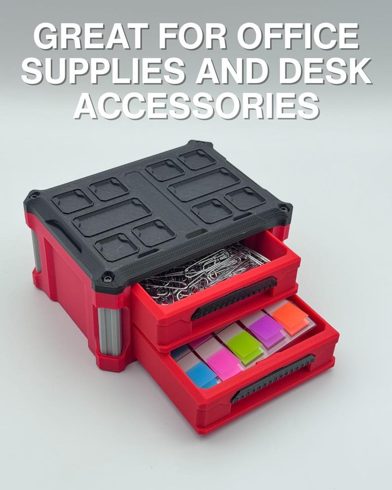 May include: Red and black two-drawer desk organiser with the text "GREAT FOR OFFICE SUPPLIES AND DESK ACCESSORIES." The top drawer contains paper clips, and the bottom drawer contains colourful sticky notes.