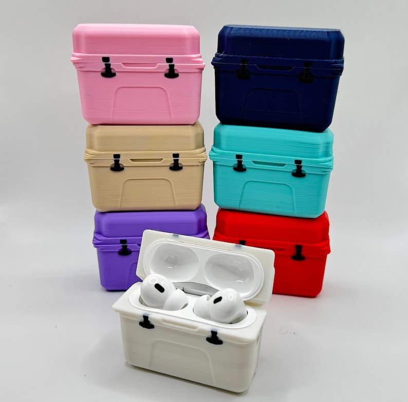 May include: A stack of colorful miniature cooler-shaped cases. The cases are in various colors, including pink, beige, purple, blue, turquoise, and red. One white case is open, revealing a pair of white earbuds. The cases have black latches.