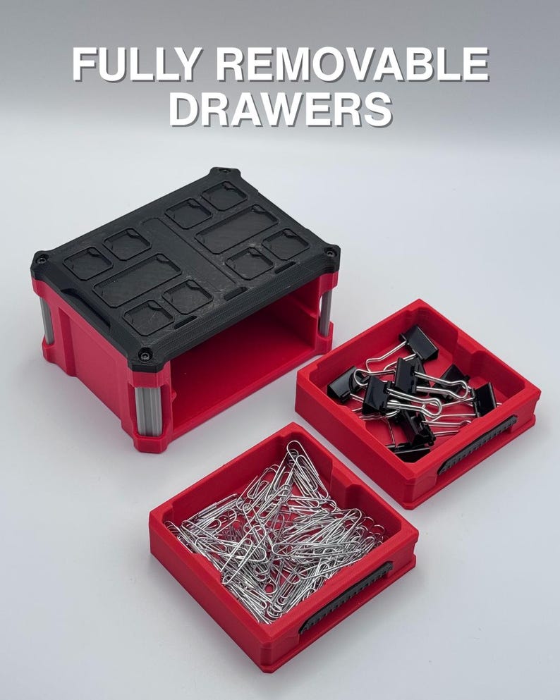 May include: A red and black storage container with the text "FULLY REMOVABLE DRAWERS". The container has a black top and red base, with two removable red drawers filled with paper clips and binder clips.