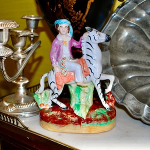 Antique Staffordshire figurine of a young rider on a zebra between lavish greenery