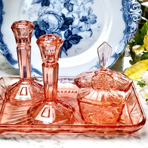 Conjunto de penteadeira vintage de vidro moldado do século XX com bandeja, castiçais e dois potes de pó em uma cor rosa pêssego brilhante