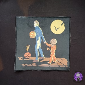 May include: A black square patch with a Halloween illustration. It shows Michael Myers and Sam from Trick 'r Treat walking together, both holding pumpkins. A full moon and bats are in the background. The patch has a black border.