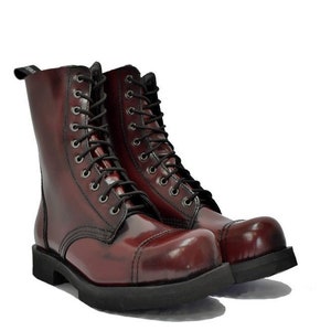 May include: A pair of burgundy leather combat boots with black laces and a black sole. The boots have a high-top design with multiple eyelets for the laces and a rounded toe.