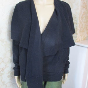 May include: A black long-sleeved cardigan with a draped collar and a deep V-neckline.