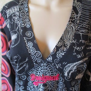 May include: Black long-sleeve shirt with a silver and white abstract print. The shirt has a V-neck and a pink "Desigual" logo on the front.