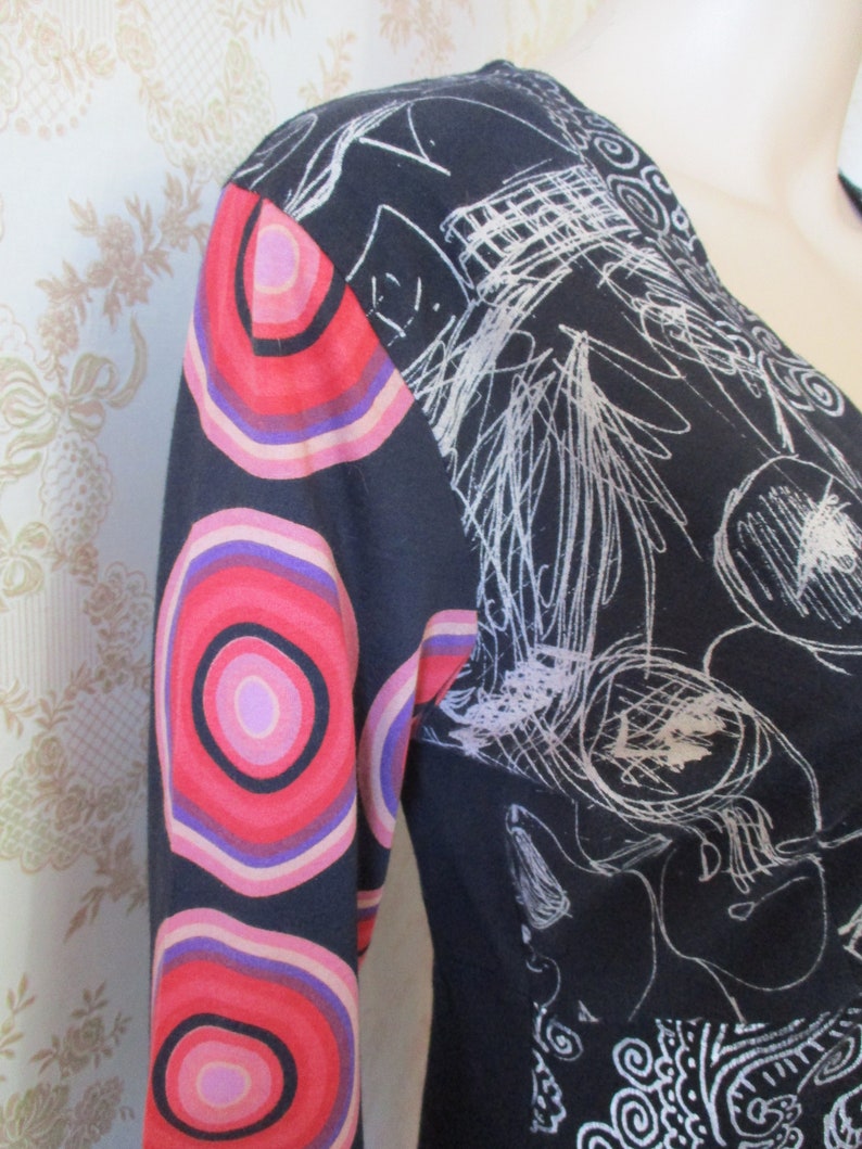 May include: Black long-sleeved dress with a white abstract design and a colorful circular pattern on the sleeves.