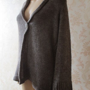 May include: A brown knitted cardigan with a single button closure and a v-neck.