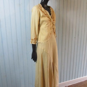 May include: A long, flowing dress in a pale yellow color with brown embroidery around the neckline and hem. The dress is made of a lightweight fabric and has a relaxed fit.