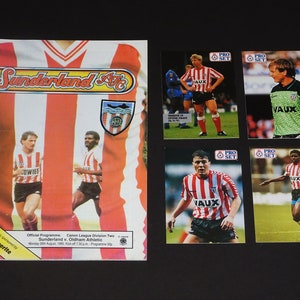 May include: A Sunderland AFC programme for a match against Oldham Athletic on 20th August, 1985. The programme cover features a red and white striped shirt with the team's logo. There are four trading cards featuring Sunderland players with the text "PRO SET" and "VAUX" on them.
