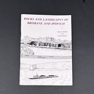 May include: A white softcover book titled ROCKS AND LANDSCAPES OF BRISBANE AND IPSWICH by Warwick Willmott and Neville Stevens. The cover features a black and white line drawing of a river, a bridge, city buildings, and a barge carrying cargo.