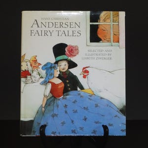 Può includere: Una copertina di libro con un'illustrazione di una ragazza con un vestito blu e un ragazzo con un cappello a cilindro e un cappotto nero. Il titolo del libro è "Hans Christian Andersen Fairy Tales" con le parole "Selected and Illustrated by Lisbeth Zwerger" sotto il titolo.