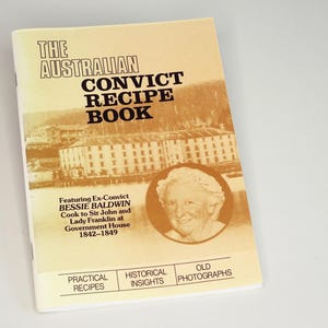 May include: A vintage cookbook titled "The Australian Convict Recipe Book" with a sepia-toned cover. The cover features text, an illustration of a building, and a portrait of Bessie Baldwin. Additional text includes "Practical Recipes", "Historical Insights", and "Old Photographs".