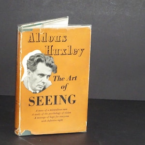 May include: A vintage book titled "The Art of Seeing" by Aldous Huxley. The book has an orange cover with black text and a portrait of a man. The book's subtitle is "A story of a miraculous cure, A study of the psychology of vision, A message of hope for everyone with defective sight."