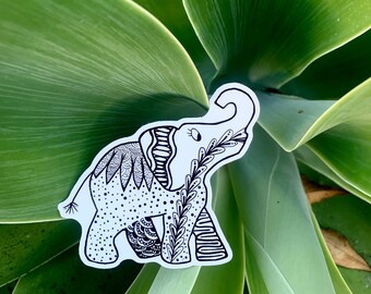 May include: A black and white line drawing of an elephant with intricate patterns and designs. The elephant is set against a backdrop of green leaves.