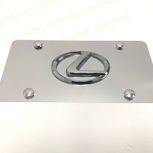 May include: Chrome license plate frame with a silver Lexus logo. The frame has four screw holes.
