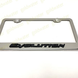 May include: A silver license plate frame with black lettering that reads "EVOLUTION".