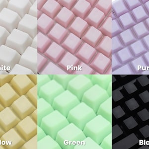 K&ouml;nnte beinhalten: Eine Sammlung farbiger Tastaturtasten in Wei&szlig;, Rosa, Lila, Gelb, Gr&uuml;n und Schwarz. Jede Farbe ist mit ihrem Namen beschriftet. Die Tasten sind quadratisch und in einem Raster angeordnet.