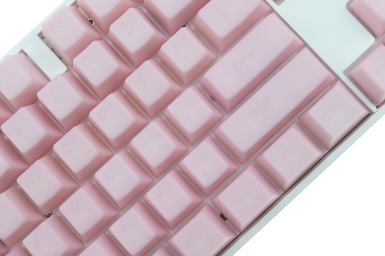 K&ouml;nnte beinhalten: Nahaufnahme einer mechanischen Tastatur mit hellrosa Tastenkappen. Die Tasten sind in einem Standard-Layout angeordnet, wobei die Tasten "Enter", "Shift" und "Strg" deutlich sichtbar sind. Die Tastatur hat einen wei&szlig;en Rahmen.