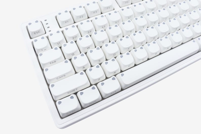 May include: A white mechanical keyboard with custom keycaps. The keycaps are white with gray accents and a unique design. The keyboard has a standard layout with function keys and a number pad.