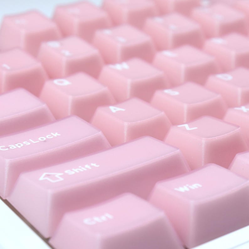 May include: Close-up of a computer keyboard with light pink keycaps. The keys are arranged in rows and columns, with white lettering. The Shift, CapsLock, Ctrl, and Win keys are visible. The keyboard has a clean, minimalist design.
