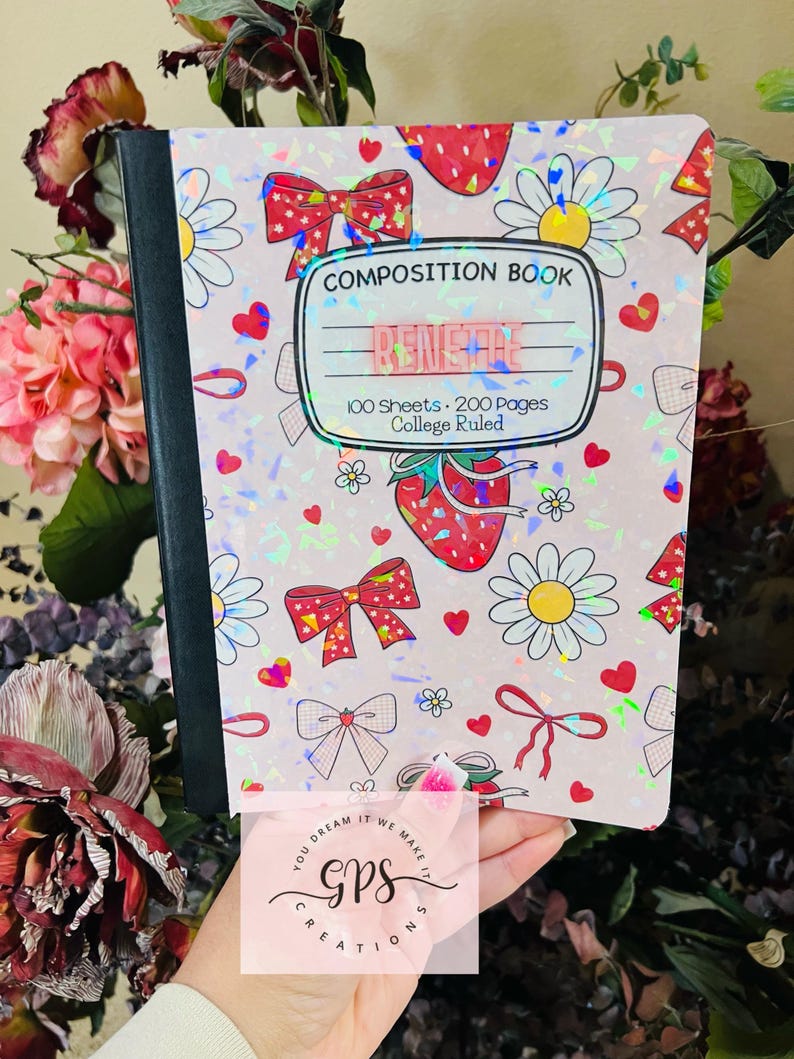 Peut inclure: Un cahier de composition avec une couverture rose orn&eacute;e de n&oelig;uds, de fraises et de marguerites. La couverture porte l'inscription "COMPOSITION BOOK", "RENSHAE" et "100 Sheets &bull; 200 Pages &bull; College Ruled". Le cahier est tenu devant un fond floral.