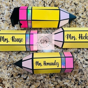 May include: Four yellow pencil-shaped boxes with pink, black, and blue accents. The boxes are decorated with the names "Mrs. Rouse", "Mrs. Hicks", "Mrs. Hernandez", and a logo that says "GPS Creations".