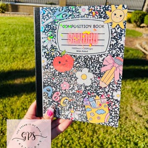 May include: A composition book with a black and white speckled cover, decorated with colorful illustrations of a sun, apple, flowers, and pencils. The cover reads "COMPOSITION BOOK" and "SANDHU". The notebook has 100 sheets and 200 pages.