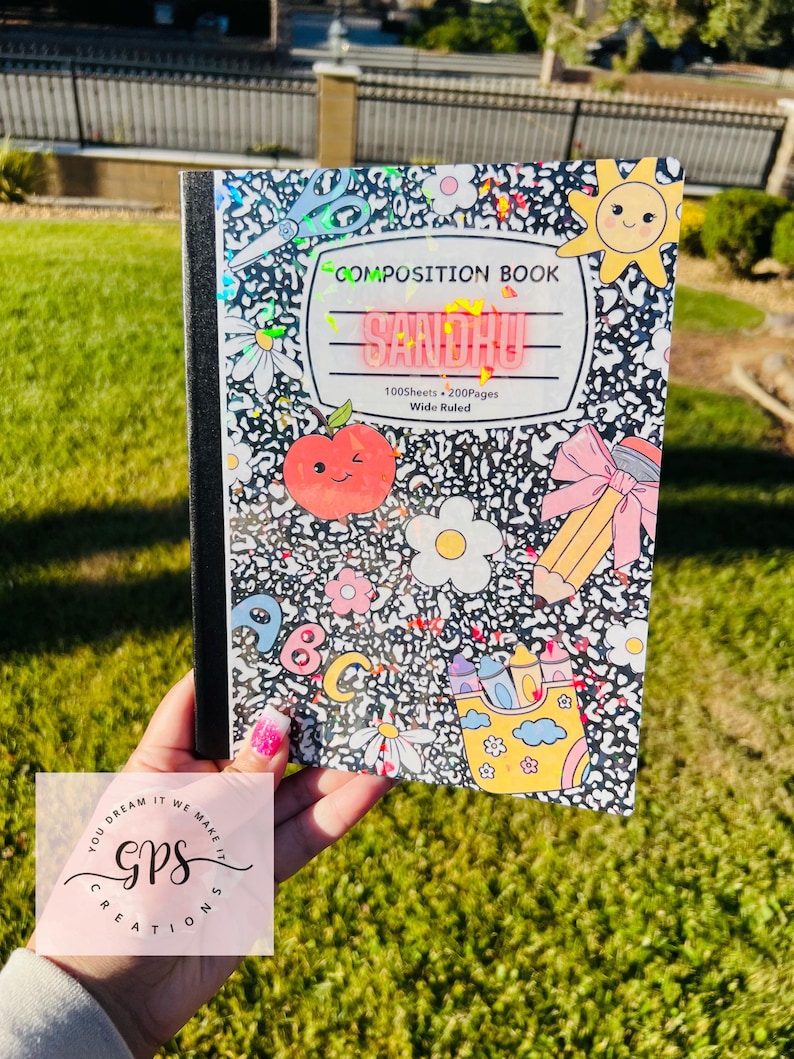 May include: A composition book with a black and white speckled cover, decorated with colorful illustrations of a sun, apple, flowers, and pencils. The cover reads "COMPOSITION BOOK" and "SANDHU". The notebook has 100 sheets and 200 pages.