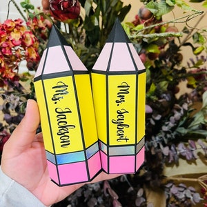May include: Two yellow pencil-shaped boxes with pink and black accents. The boxes are decorated with the names "Mrs. Seyfert" and "Mrs. Jackson".