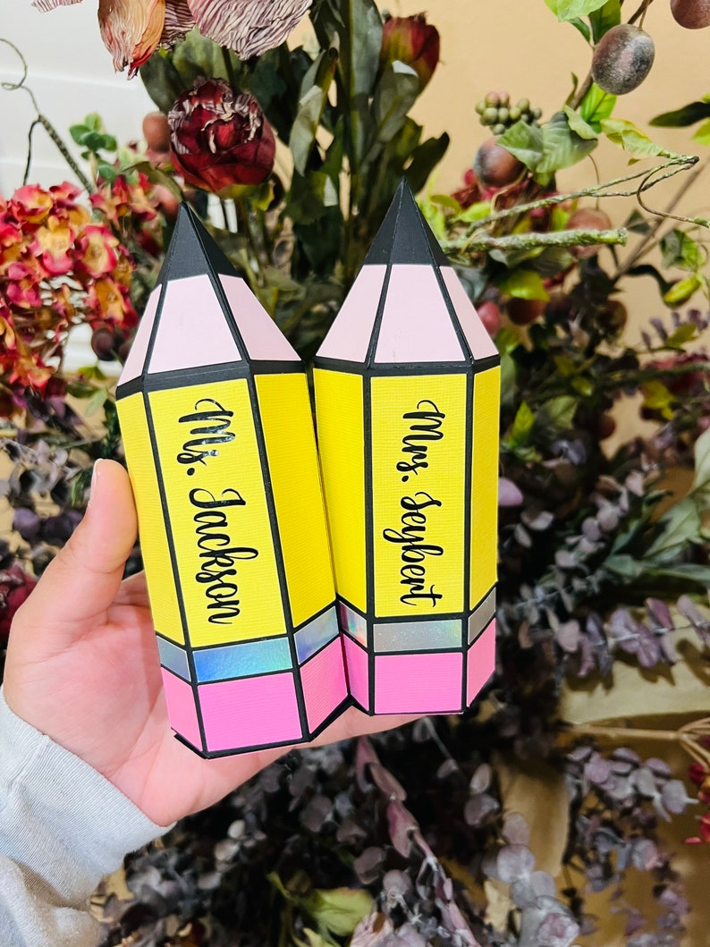 May include: Two yellow pencil-shaped boxes with pink and black accents. The boxes are decorated with the names "Mrs. Seyfert" and "Mrs. Jackson".