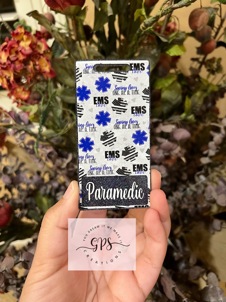 May include: A black and white patterned key chain with a blue star of life and the text "EMS Saving Lives One At A Time" and "Paramedic".
