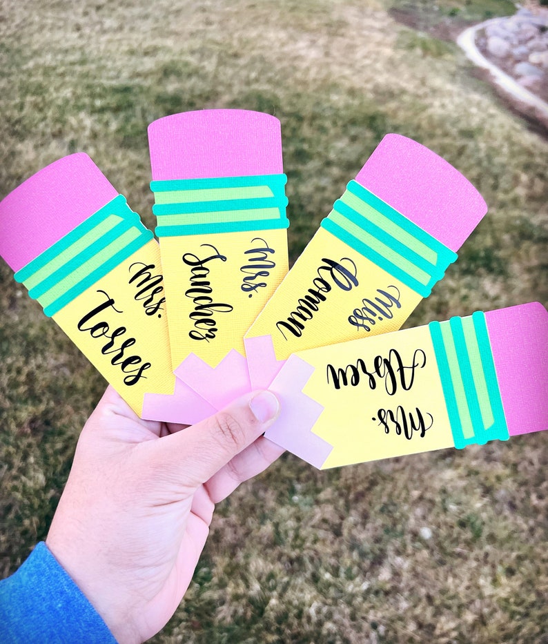 Pu&ograve; includere: Cinque carte gialle a forma di matita con gomme rosa e strisce verdi. Ogni carta ha il nome di un insegnante scritto in corsivo nero: "Miss Torres", "Miss Sanchez", "Miss Bowman", "Miss Ogden" e "Miss Green".