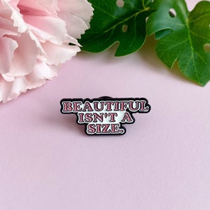 Pin esmaltado rosa, branco e preto "Bonito não tem tamanho"